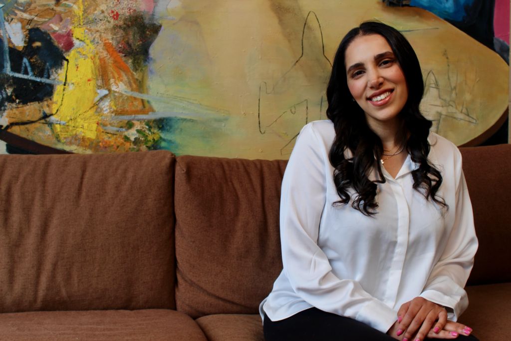 Photo of Roxana “Roxy” Radnia Abergel smiling while sitting on a couch