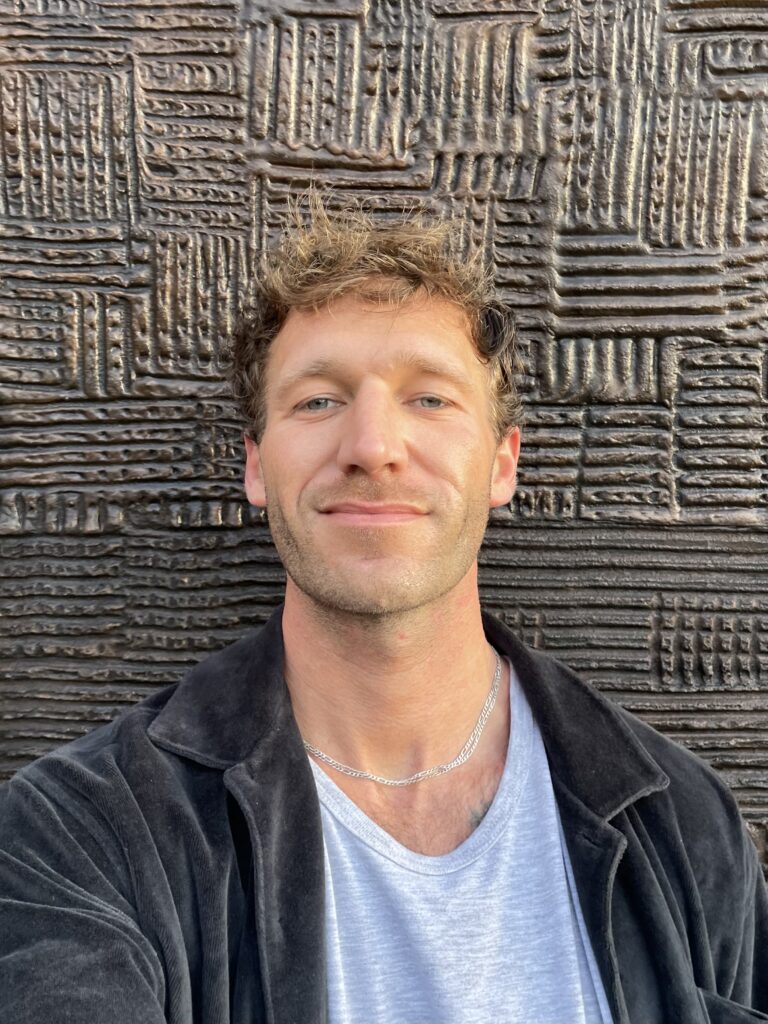 Kellen Hubbard smiling in-front of a textured wall