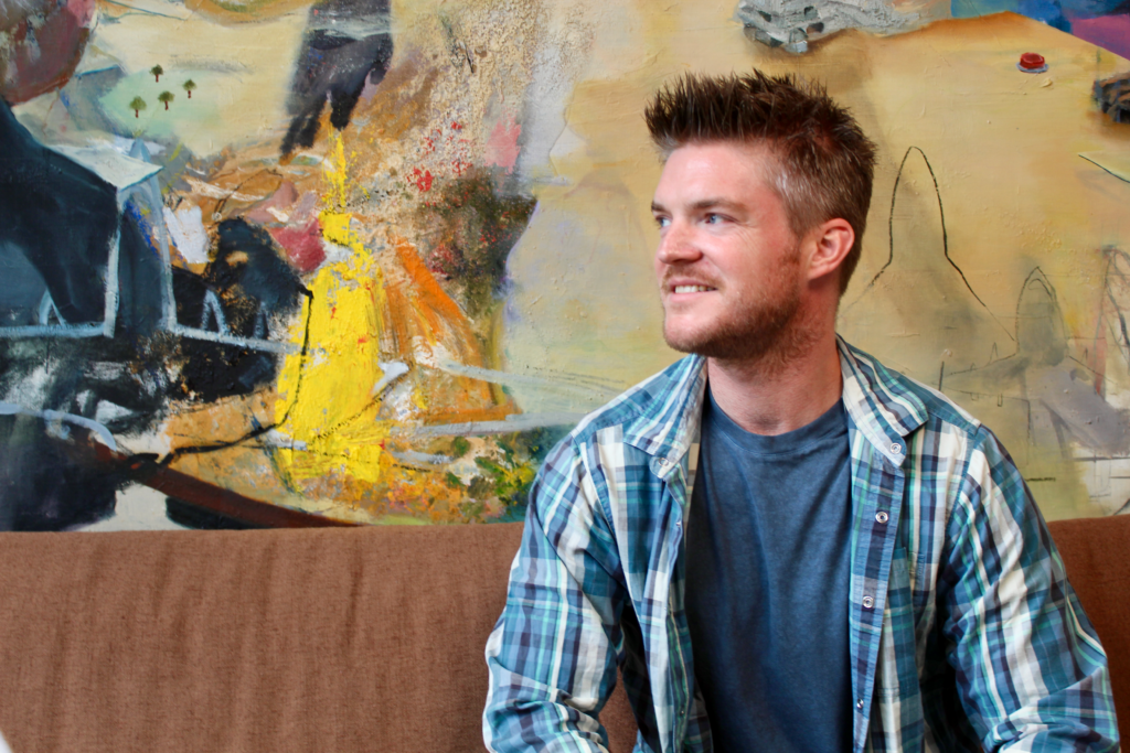 Adam Louis Ayer smiling while sitting on a couch